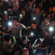 Mobile phones illuminate the scene.